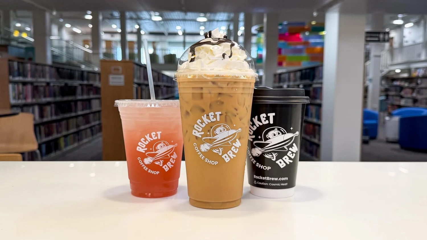 Three Rocket Brew drinks on the counter inside the library coffee shop